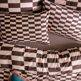 Checkerboard Cotton Blend Pillowcase Pair in Berry Brownie, pink and brown block prints on bedding with matching striped sheet and teal cushion.