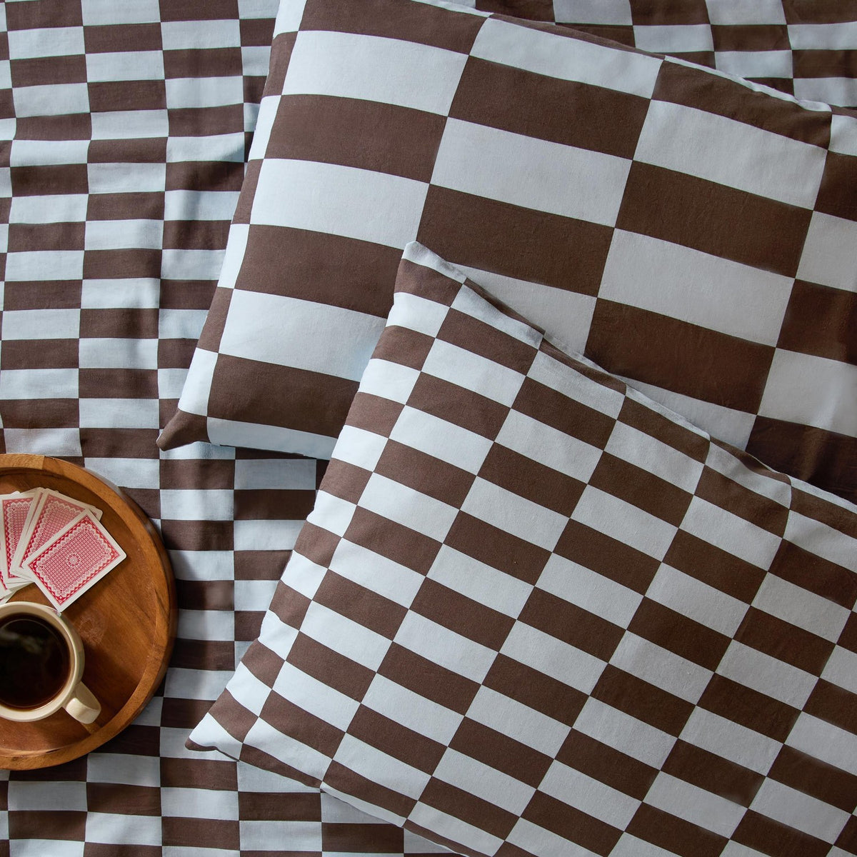 Checkerboard cotton blend pillowcase pair in blueberry muffin, brown and white oblong check pattern with mini and maxi scale reversible sides, styled on matching bedding.