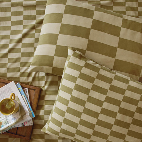 Green and cream checkerboard cotton blend pillowcase pair in Green Tea, shown on a bed with matching duvet, styled with a tray, mug, and magazines.