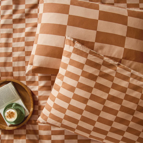 Checkerboard cotton blend pillowcase pair in Pumpkin Spice, shown in mini and maxi check patterns on a matching terracotta and peach bedding set in a bedroom setting.