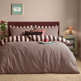 Ultimate Stripe Reversible Duvet Cover Set in Berry Brownie shown on a bed with matching pillowcases, featuring bold brown and pink striped bedding in a bedroom setting.