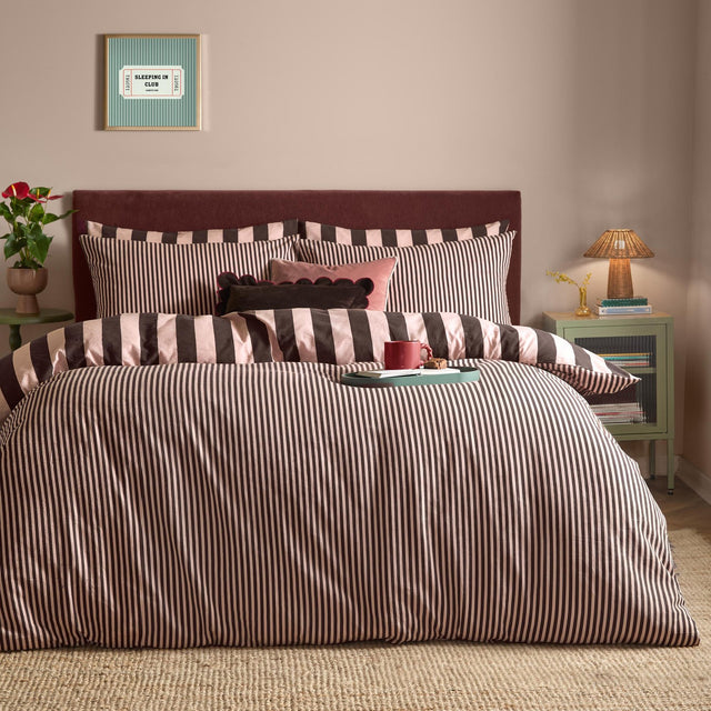Ultimate Stripe Reversible Duvet Cover Set in Berry Brownie shown on a bed with matching pillowcases, featuring bold brown and pink striped bedding in a bedroom setting.