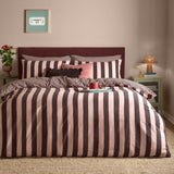 The Ultimate Stripe Reversible Duvet Cover Set in Berry Brownie, styled on a bed with bold brown and pink striped bedding, matching pillowcases, and accent cushions in a bedroom setting.
