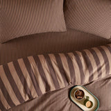 The Ultimate Stripe Reversible Duvet Cover Set in Chocolate Truffle, shown on a bed with pinstripe and wide-stripe sides in chocolate brown and caramel tones.