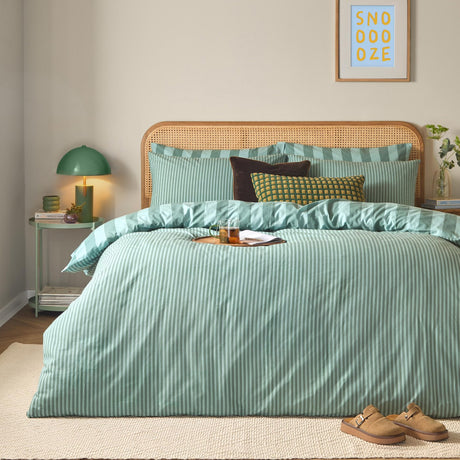 The Ultimate Stripe Reversible Duvet Cover Set in peppermint green on a bedroom bed with rattan headboard, striped pillowcases, and coordinating scatter cushions.