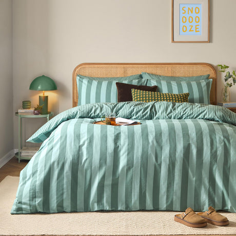 The Ultimate Stripe Reversible Duvet Cover Set in peppermint green with bold wide-stripe design, styled on a bed with matching pillowcases and cushions in a bedroom setting.