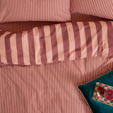 The Ultimate Stripe Reversible Duvet Cover Set in Raspberry Smoothie, showing bold wide-stripe pillowcases against a narrow pinstripe cover in dusky pink and blush tones on a bed.