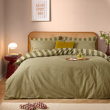 Green tea striped reversible cotton duvet cover set styled on a bed with matching pillowcases and a rattan headboard in a pink-toned bedroom.