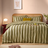 Green tea striped reversible cotton duvet cover set on a bed with rattan headboard, styled with a mustard cushion in a cosy pink bedroom setting.