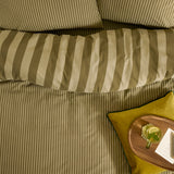 The Ultimate Stripe Cotton Reversible Duvet Cover Set in Green Tea, shown on a bed with striped pillowcases and a mustard cushion beside a wooden tray.