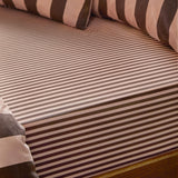 Fitted sheet in a fine pink and brown tonal stripe cotton blend, shown on a mattress with matching striped pillows in the background.