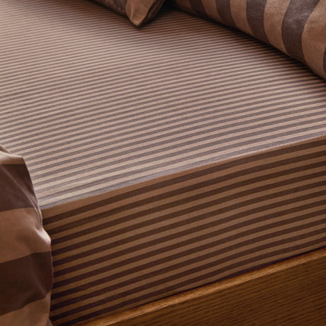 The Ultimate Stripe Cotton Blend Fitted Sheet in Chocolate Truffle, close-up of tonal brown striped fabric on a mattress with a wooden bed frame.