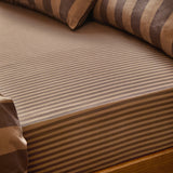 Close-up of The Ultimate Stripe Cotton Blend Fitted Sheet in Chocolate Truffle, showing fine tonal brown stripes and the fitted corner on a mattress with matching striped cushions.