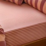 The Ultimate Stripe Cotton Blend Fitted Sheet in Raspberry Smoothie, fitted on a bed with matching striped pillows in a tonal pink and burgundy narrow stripe pattern.