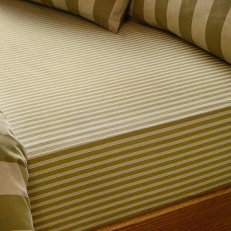 Fitted sheet in green and cream tonal stripe cotton-polyester blend, shown on a bed with matching striped pillowcases and a wooden bed frame.