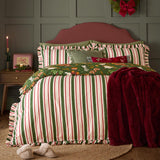 Twelve Days Frill Cotton Striped Duvet Cover Set in green, red and cream stripes with scalloped ruffle edges, styled on a bed with a green Christmas print reverse and burgundy throw.
