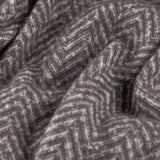 Close-up of the Tweedie Herringbone Polyester Throw in charcoal, showing the folded fabric with a two-tone grey chevron weave pattern.
