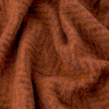 Close-up of the Tweedie Herringbone Polyester Throw in cinnamon, showing draped folds of soft, textured rust-brown fabric with a subtle herringbone weave.