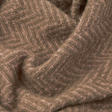Close-up of the Tweedie Herringbone Polyester Throw in mocha brown, showing its textured chevron weave draped in soft folds.