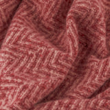 Close-up of the Tweedie Herringbone Polyester Throw in pink and burgundy, showing the woven zigzag chevron texture in soft folds.