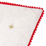 Close-up of the Twinkling Tree Velvet Linen Cushion in natural linen-look fabric with a gold embroidered star and red pom-pom trim edging, shown on a white background.