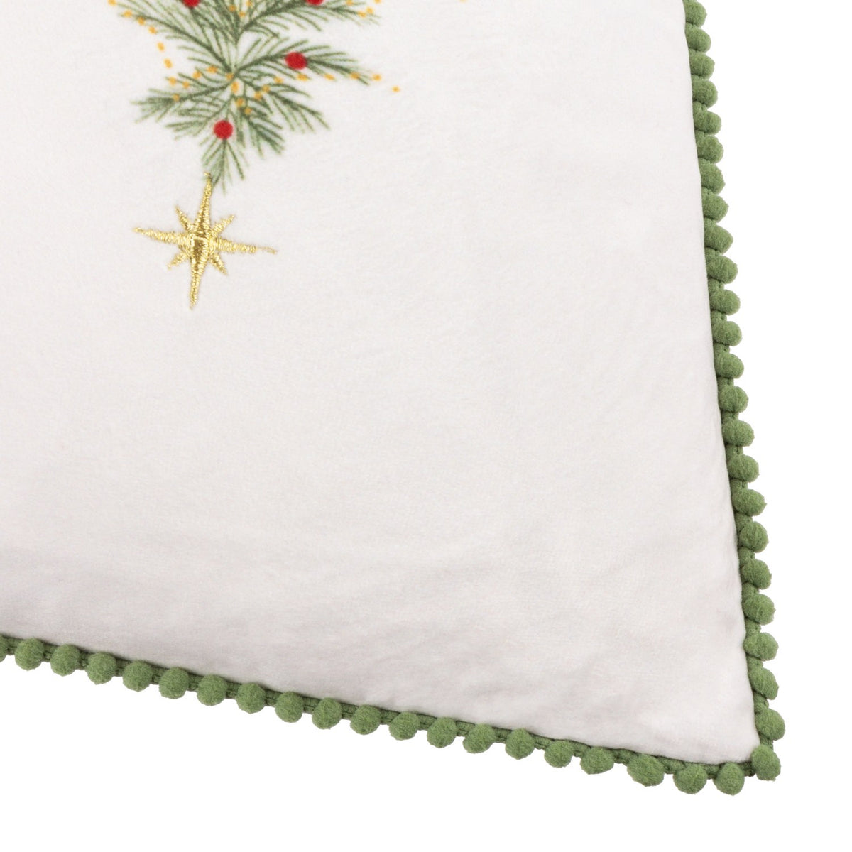Corner detail of the Twinkling Tree Woodland Velvet Cushion in cream, showing embroidered pine, berries, a gold star, and green pompom trim edging.