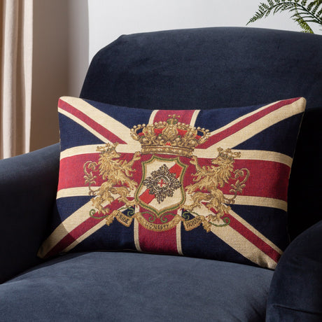 Union Jack Jacquard Cotton Cushion in navy, red and cream, with a gold crown, lions and shield crest, shown on a dark blue armchair.