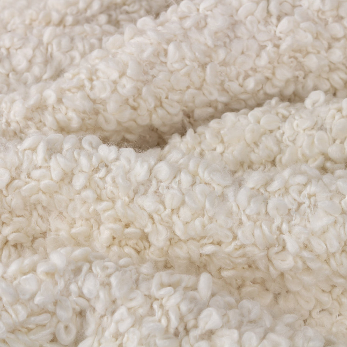 Close-up of the Ulsmere Reversible Wool Throw in ecru, showing an oversized bouclé looped texture in soft cream fabric.