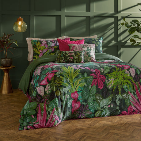 Veadeiros cotton duvet cover set with dense green botanical print and pink and blush leaf motifs, styled with matching pillowcases on a bed in a dark green panelled bedroom.