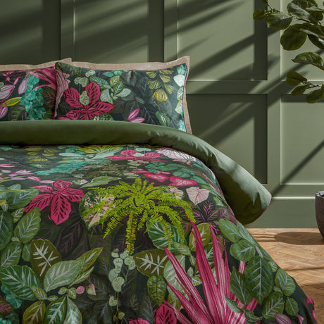 Veadeiros cotton duvet cover set with dense botanical print in green, pink and teal tones, shown on a bed with matching pillowcases in a green-panelled bedroom.