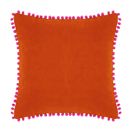 Square velvet cotton cushion in burnt orange with fuchsia pompom trim edging, shown on a plain white background.