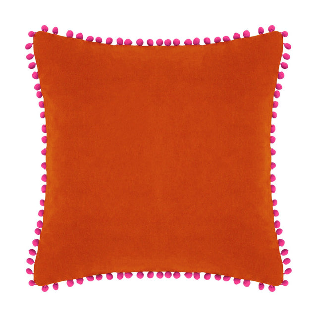 Square velvet cotton cushion in burnt orange with fuchsia pompom trim edging, shown on a plain white background.