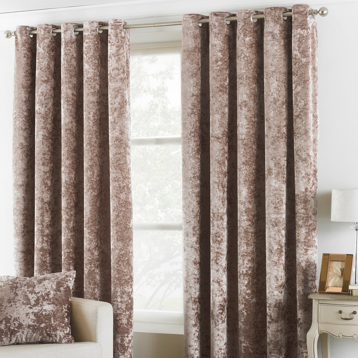 Verona Velvet Fully Lined Eyelet Curtains in Oyster, crushed velvet fabric with eyelet heading on a metal pole, shown in a living room beside a sheer white blind.