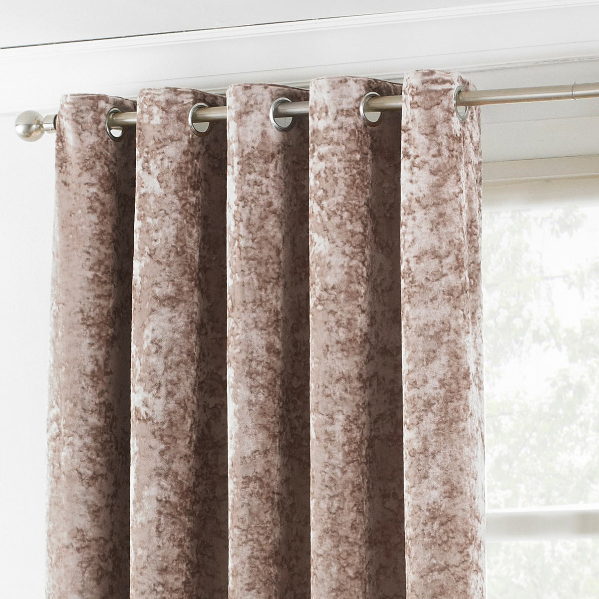 Verona Velvet Fully Lined Eyelet Curtains in Oyster, crushed velvet fabric with mottled shimmer, silver eyelet heading on a metal pole beside a window.