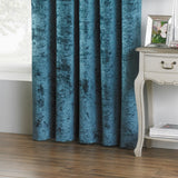 Verona Velvet Fully Lined Eyelet Curtains in teal, crushed-velvet fabric with eyelet heading, shown hanging in a living room beside a white side table.