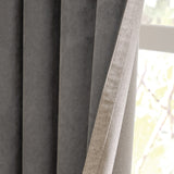 Close-up of Verso Reversible Eyelet Curtains showing charcoal suede-effect fabric folded back to reveal the natural putty-toned reverse side, hanging near a window.