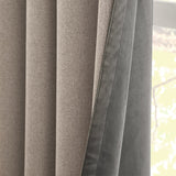 Close-up of Verso Reversible Eyelet Curtains showing charcoal suede-effect fabric on one side and natural putty weave on the reverse, hanging near a window.