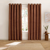 Verso Polyester Blackout Eyelet Curtains in cinnamon hung either side of a window in a living room, showing the velvety brown fabric and eyelet header on a metal pole.