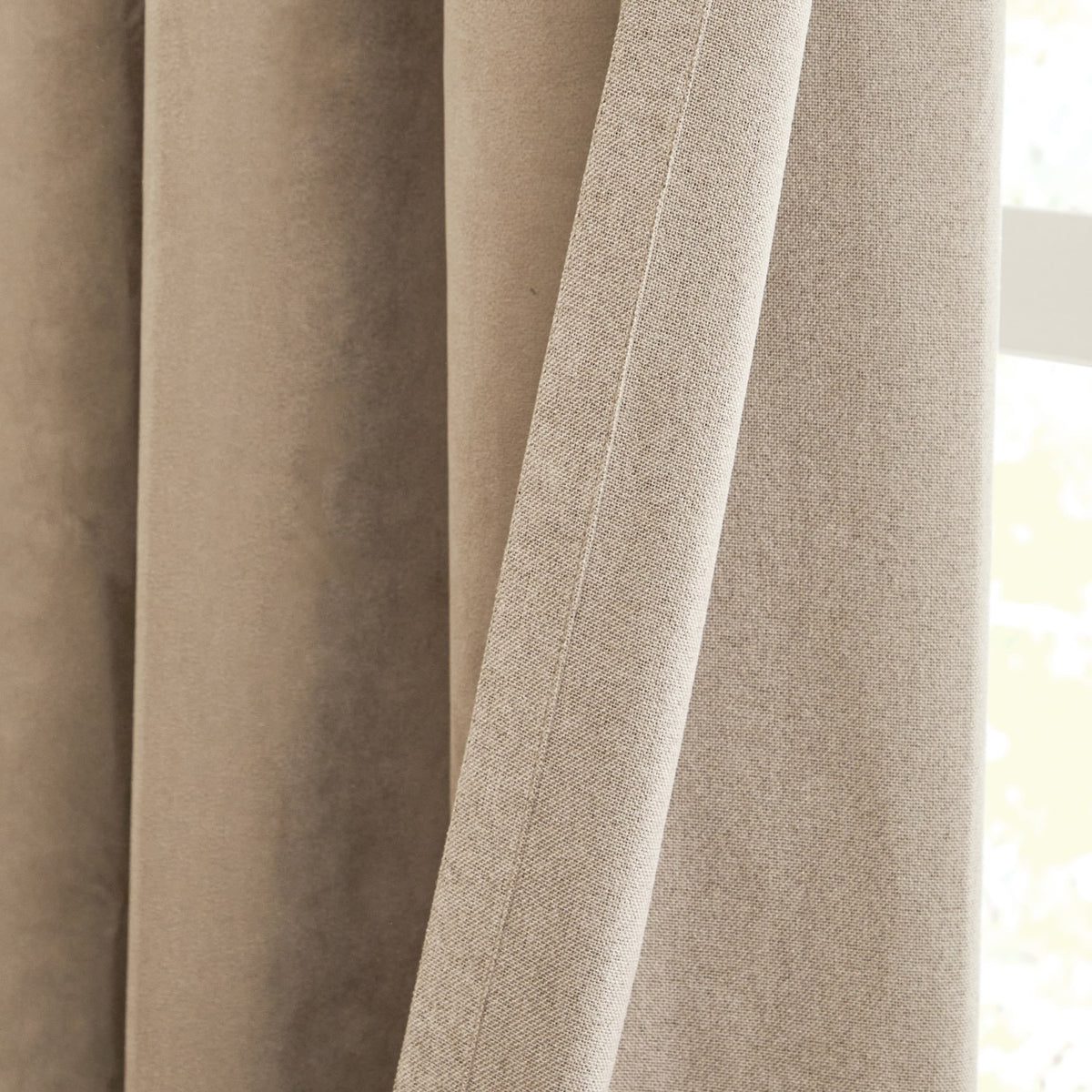 Close-up of Verso reversible eyelet curtains in mocha, showing the smooth suede-effect face and the textured woven reverse side with a folded edge seam.