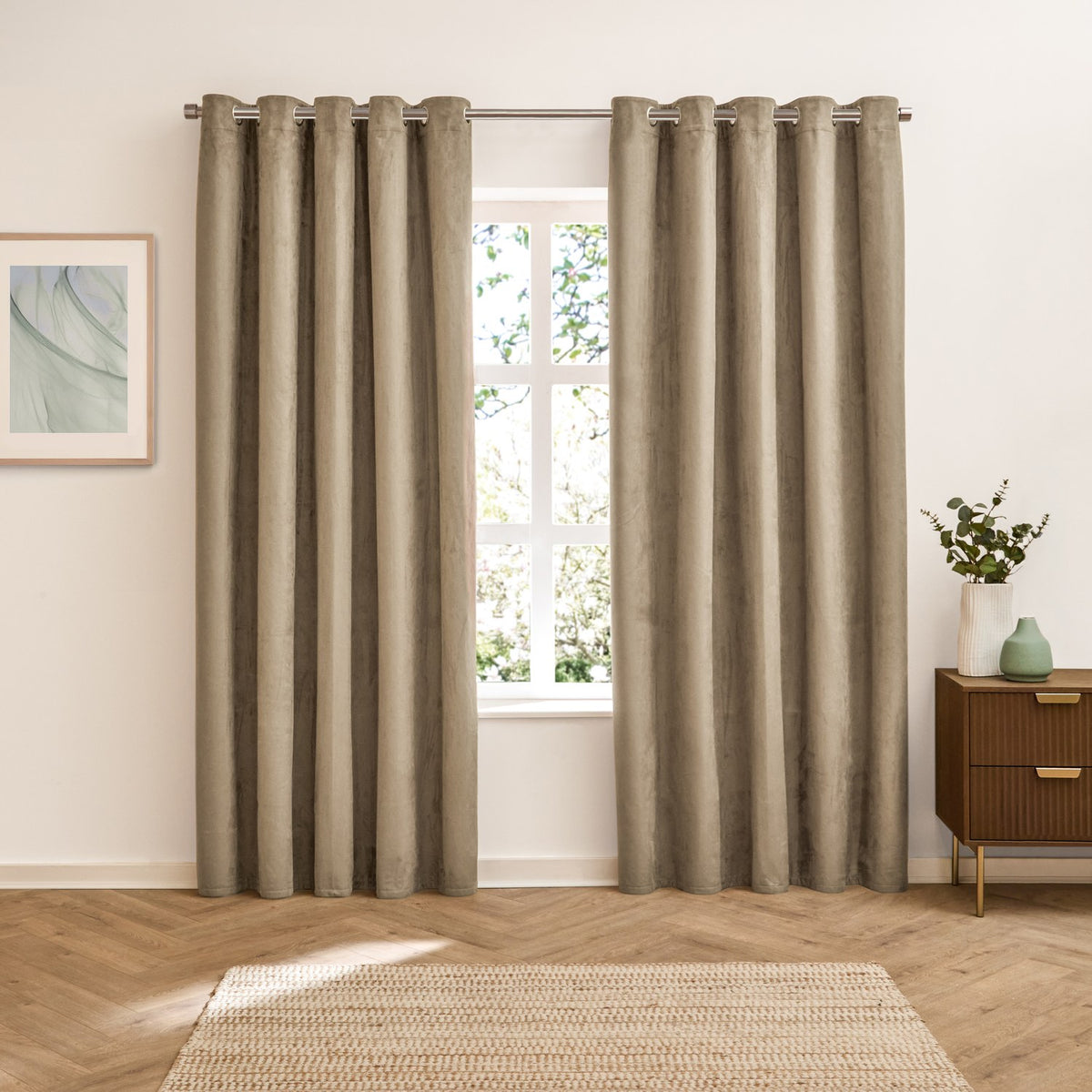 Verso Plain Reversible Eyelet Curtains in mocha, floor-length pair with silver eyelet rings on a rod, shown in a living room beside a window and wooden sideboard.