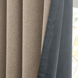 Close-up of Verso reversible eyelet curtain fabric, showing the natural oatmeal woven face folded back to reveal the petrol blue suede-look reverse side.