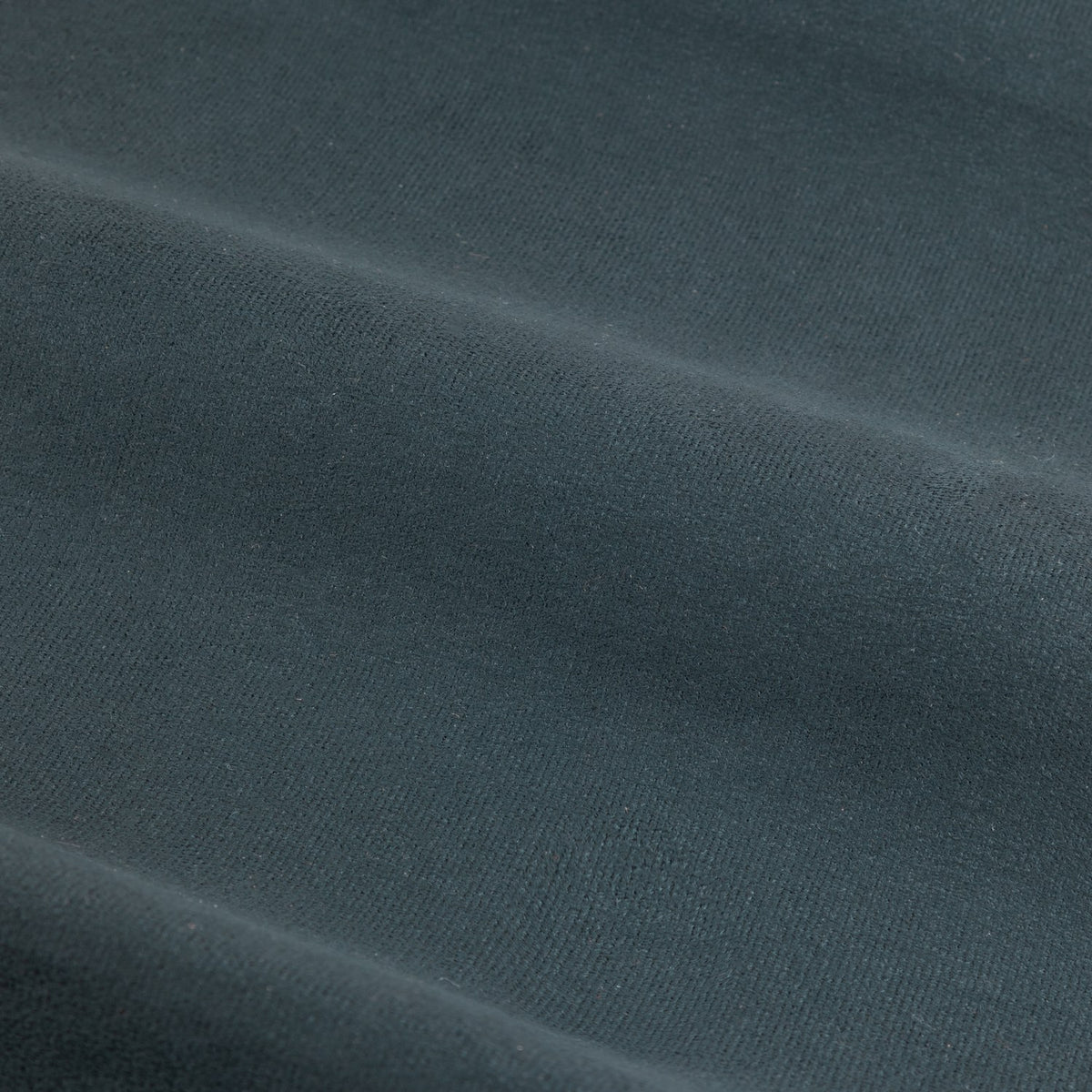 Close-up of Verso reversible eyelet curtain fabric in petrol blue, showing a soft suede-look woven surface with visible fold lines.