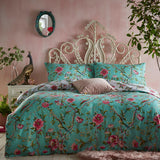 Vintage Chinoiserie Printed Floral Duvet Cover Set in jade green with pink blooms and bird motifs, shown on a bed with matching pillowcases in a pink-toned bedroom.