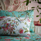 Vintage Chinoiserie Duvet Cover Set in jade with pink floral vines and bird print, shown on a bed with matching pillowcases against a pink wall.