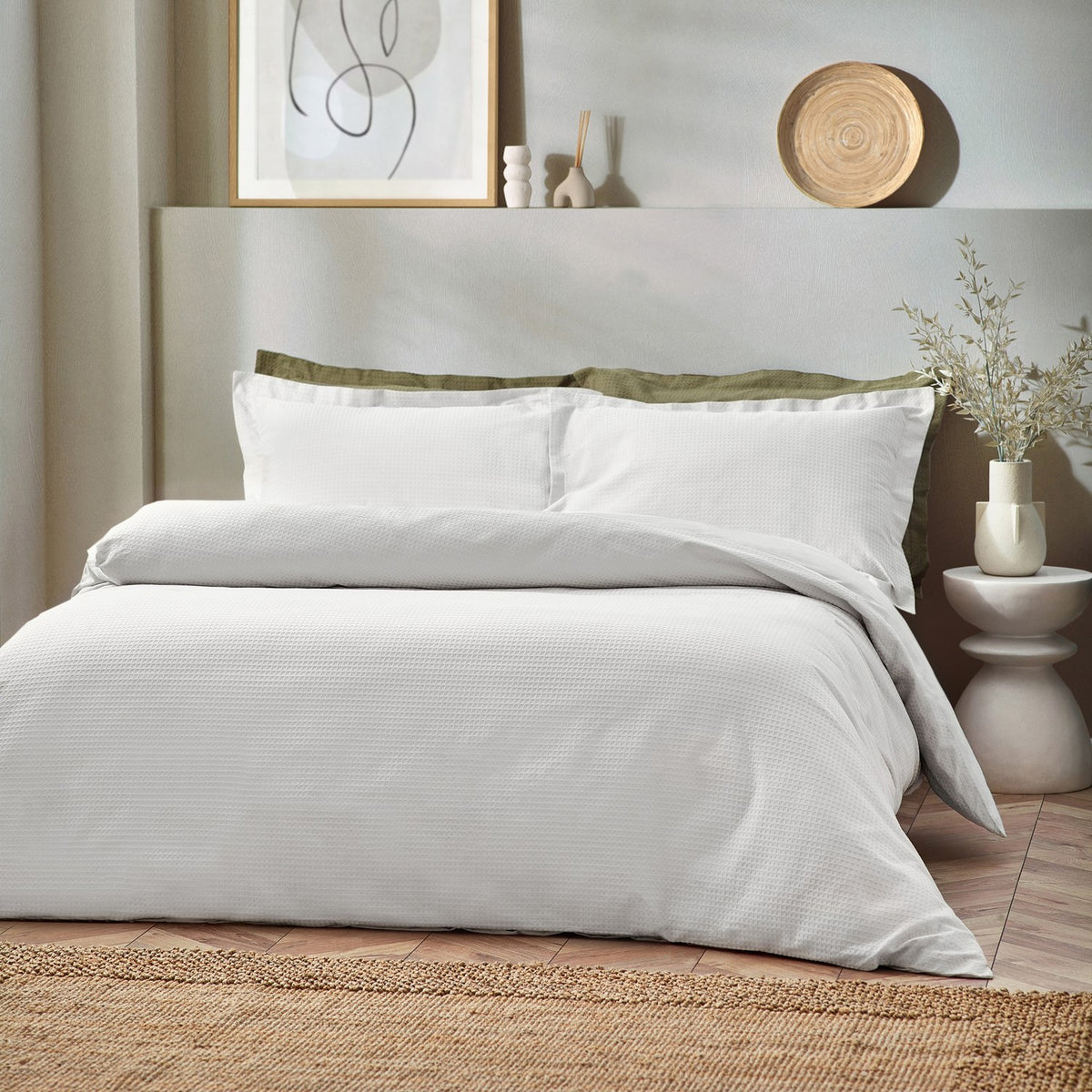 White waffle-textured cotton duvet cover set on a bedroom bed with matching pillowcases, styled with olive-trimmed pillows and neutral decor.