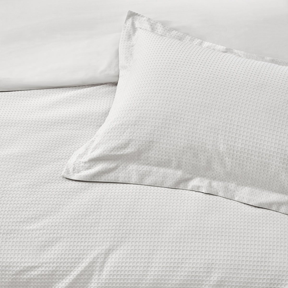 Close-up of the Waffle Cotton Plain Duvet Cover Set in white, showing a textured, dimpled weave on the duvet cover and matching pillowcase.