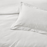 Close-up of the Waffle Cotton Plain Duvet Cover Set in white, showing a textured, dimpled weave on the duvet cover and matching pillowcase.