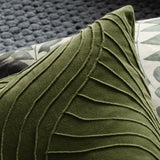 Close-up of the Waterfall Abstract Velvet Cushion in sage green, showing raised pintuck lines fanning across the velvet corner, styled beside a leaf-print pillow.