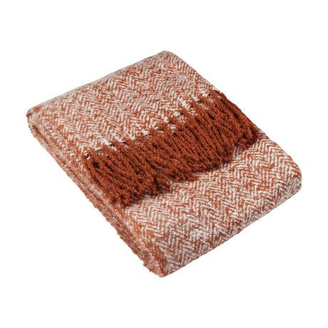 Weaver Geometric Wool Throw in rust, folded to show a herringbone chevron weave in rust and cream with twisted fringe edging, set against a plain white background.