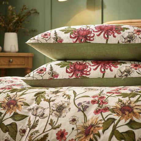 Wallflower Cotton Botanical Duvet Cover Set in Natural, cream cotton-blend bedding with sunflowers, chrysanthemums and poppies in red, gold and green, shown with matching pillowcases on a bed.